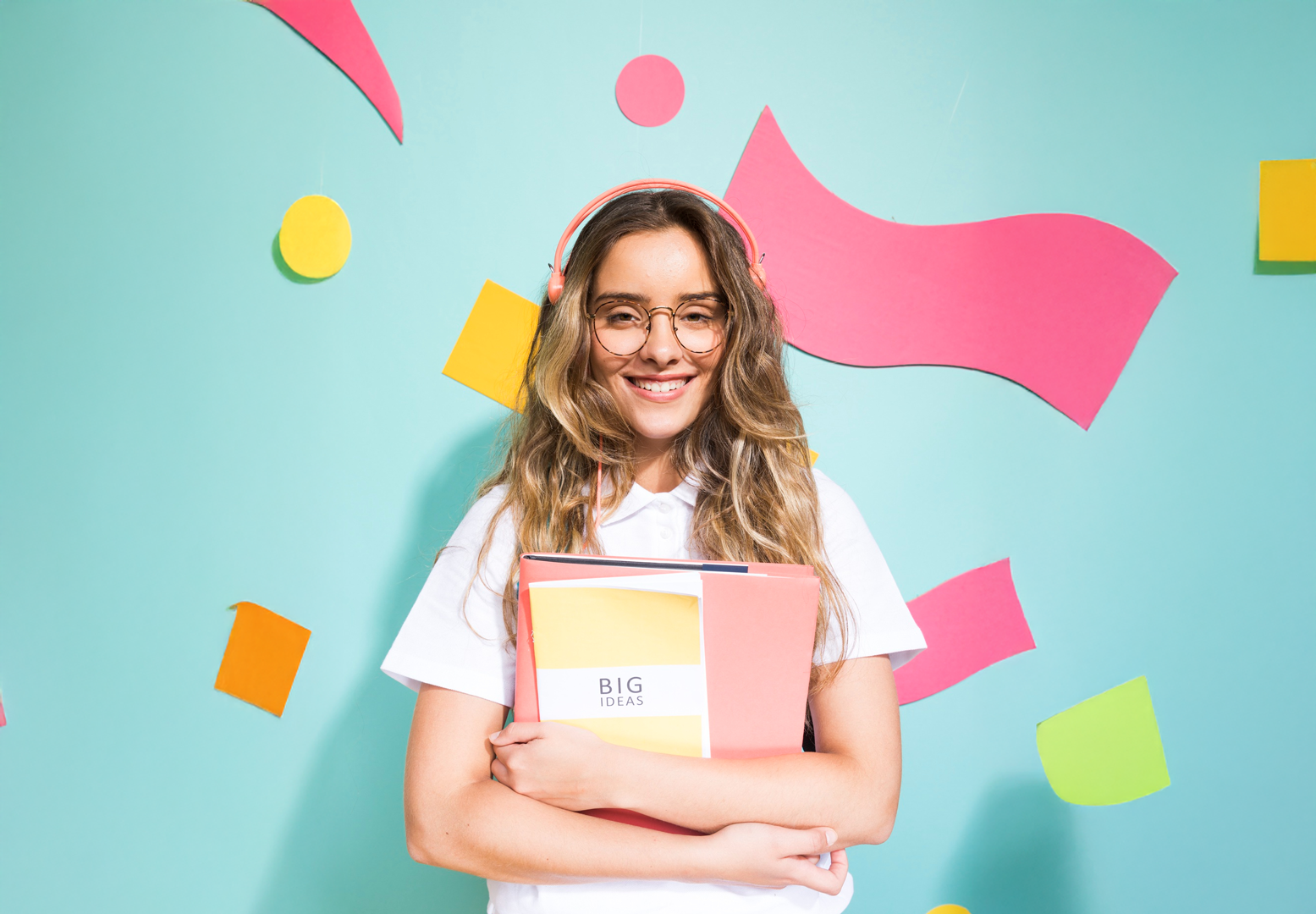 Woman holding notepads with 'Big Ideas' written on them, bold geometric shapes in the background