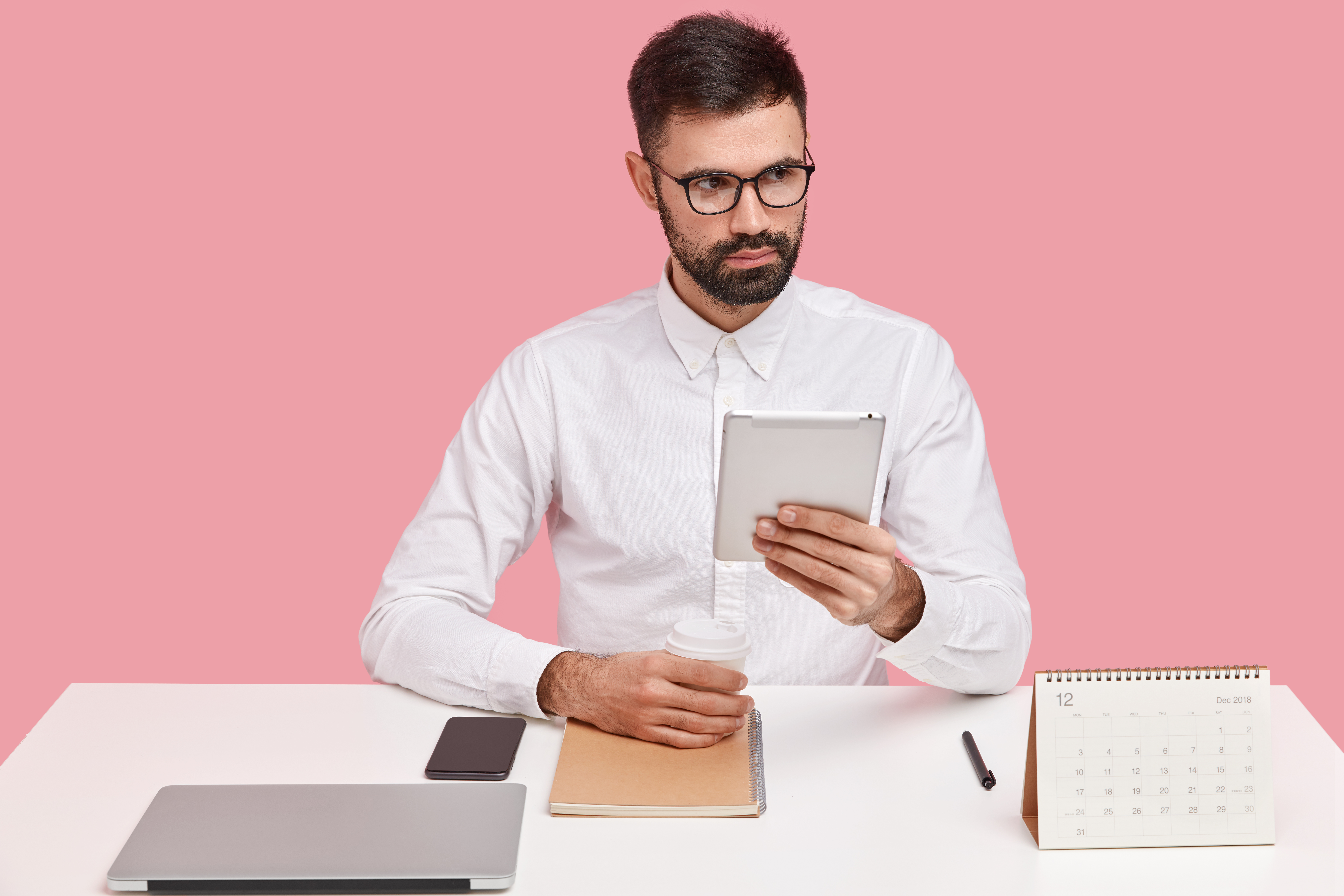 Man looking at an iPad doing calculations with focus and precision.